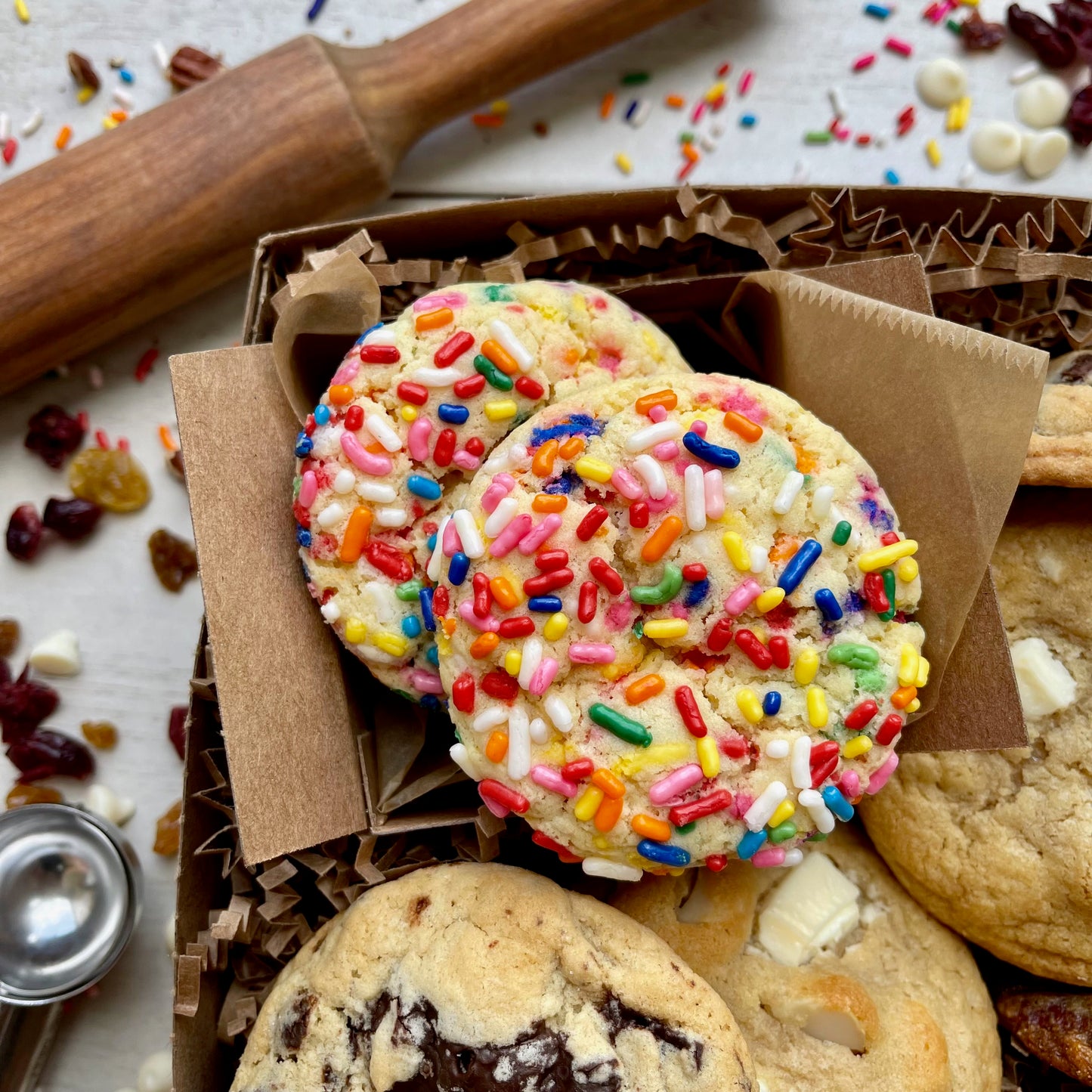 Assorted gift box with sprinkle cookies, chocolate chip cookies, white chocolate macadamia cookies, and oatmeal raisin cookies.