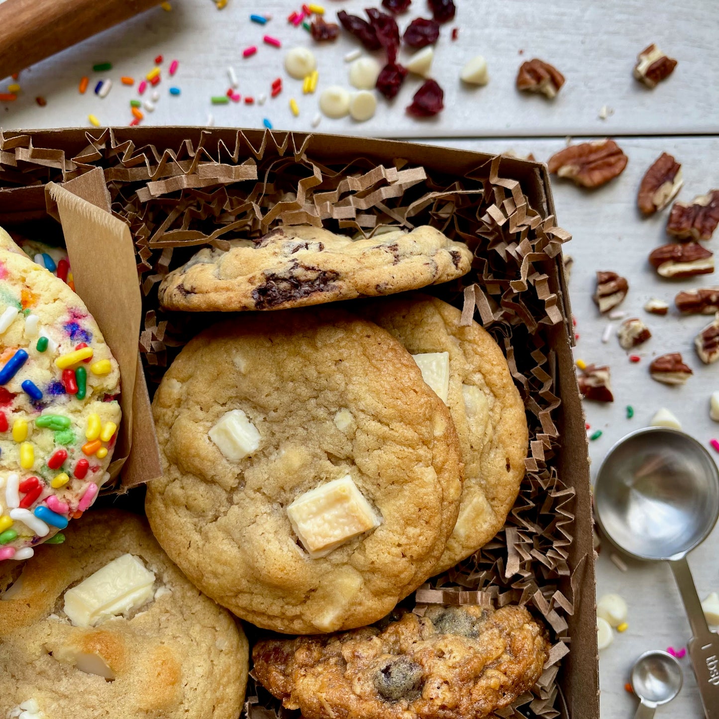 Assorted gift box with sprinkle cookies, chocolate chip cookies, white chocolate macadamia cookies, and oatmeal raisin cookies.