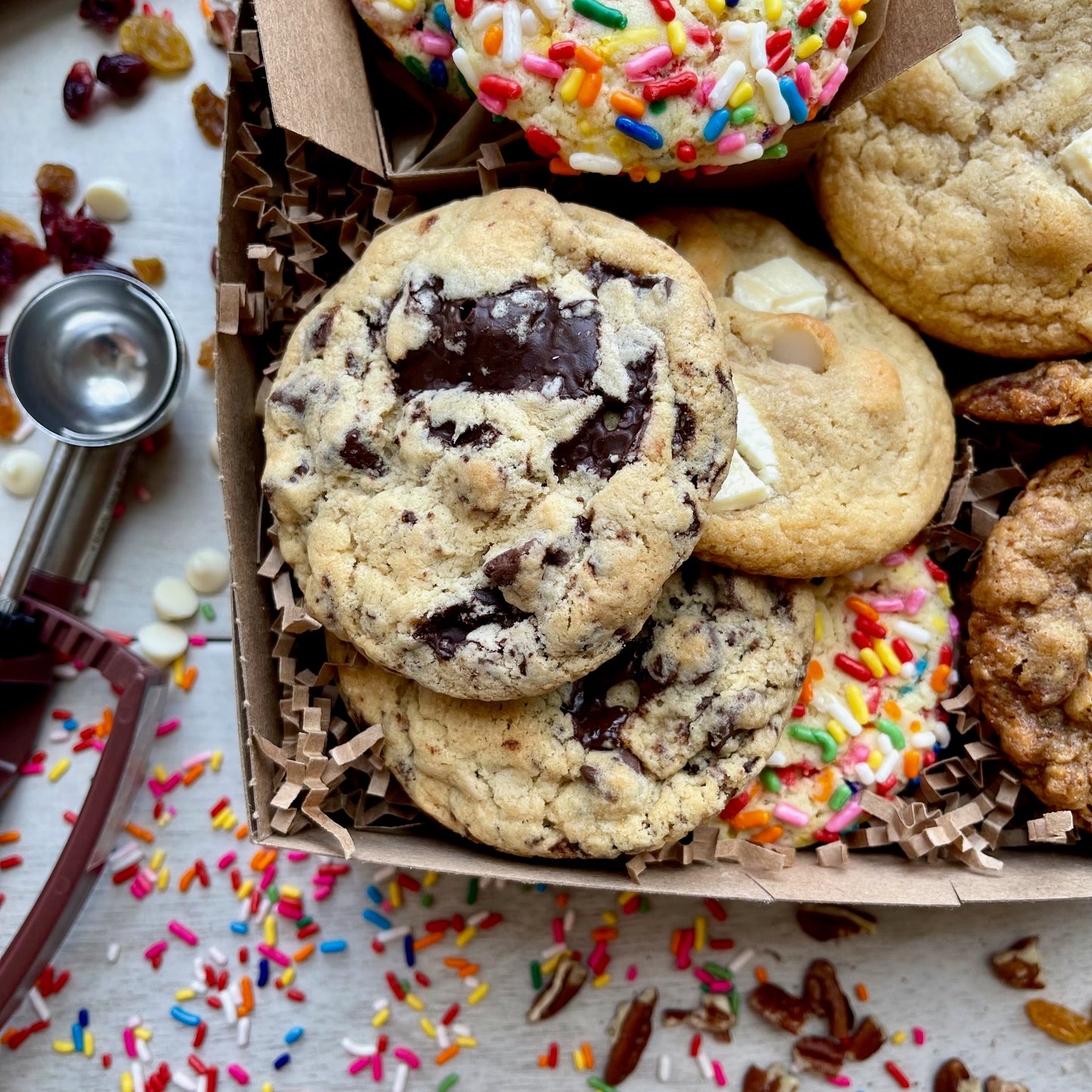 Assorted gift box with sprinkle cookies, chocolate chip cookies, white chocolate macadamia cookies, and oatmeal raisin cookies.