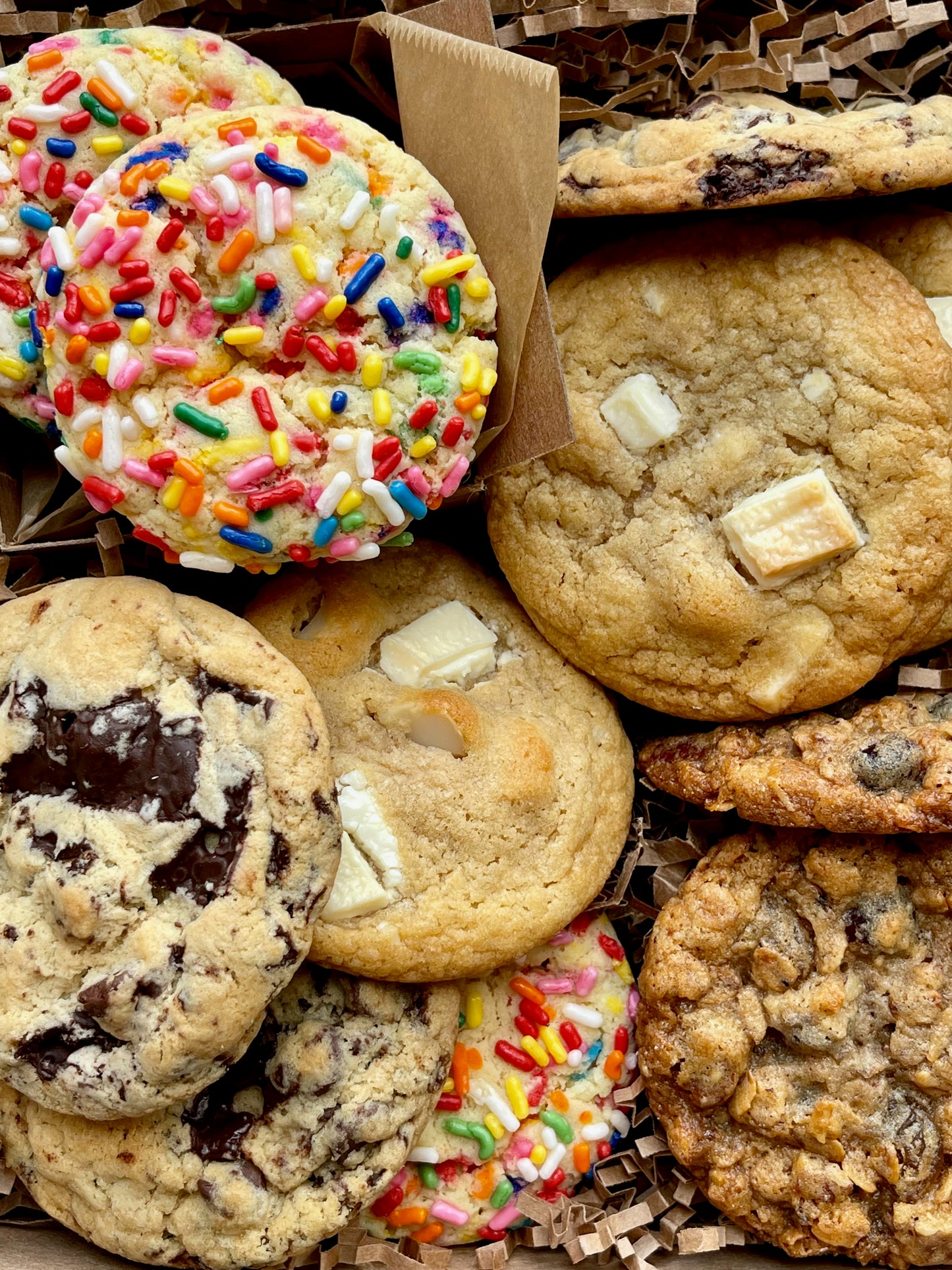 Assorted gift box with sprinkle cookies, chocolate chip cookies, white chocolate macadamia cookies, and oatmeal raisin cookies.