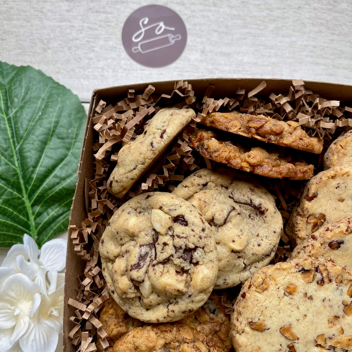 Assorted cookie gift box with maple pecan shortbread, double chocolate macadamia cookies, oatmeal raisin pecan cookies, and chocolate walnut cherry cookies.