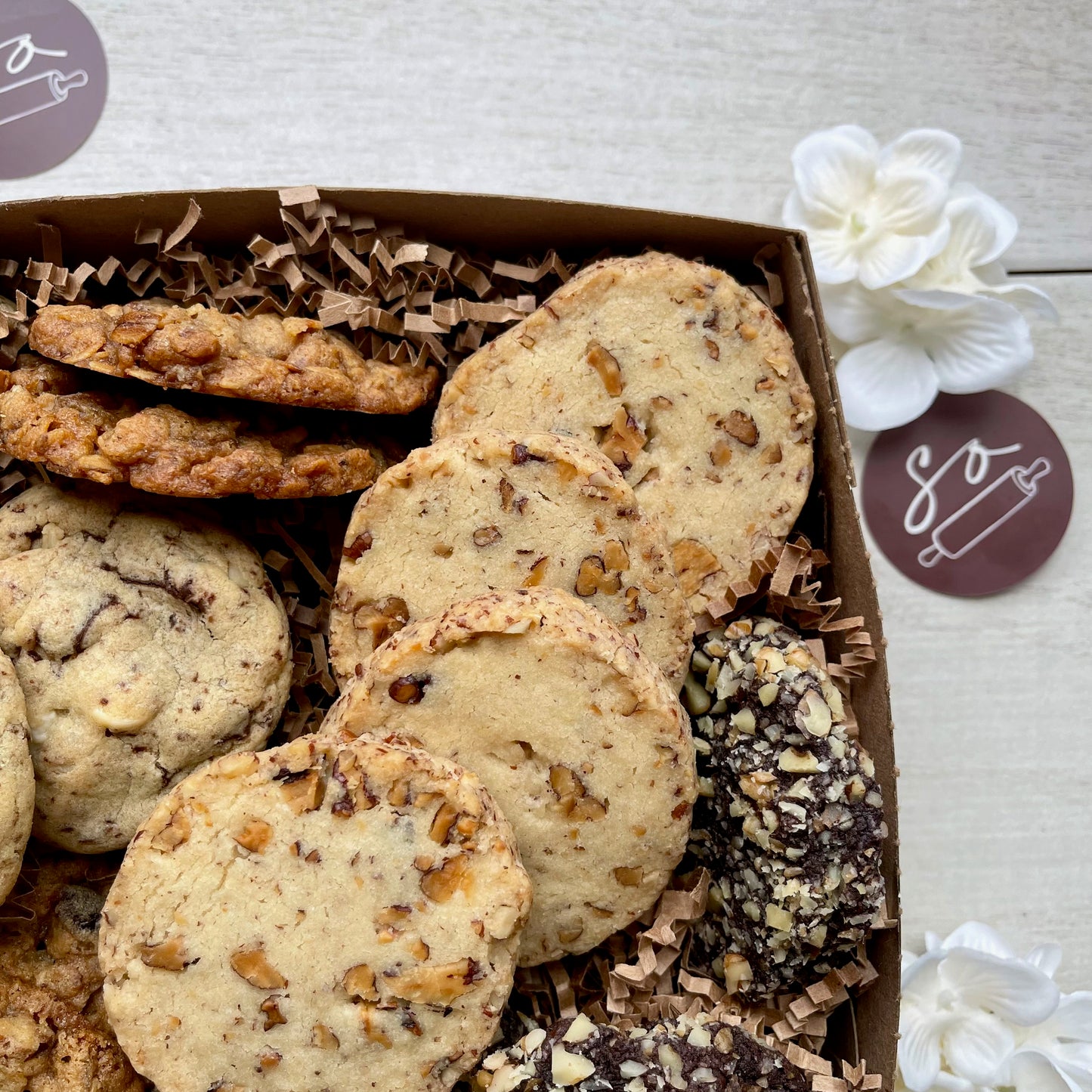 Assorted cookie gift box with maple pecan shortbread, double chocolate macadamia cookies, oatmeal raisin pecan cookies, and chocolate walnut cherry cookies.