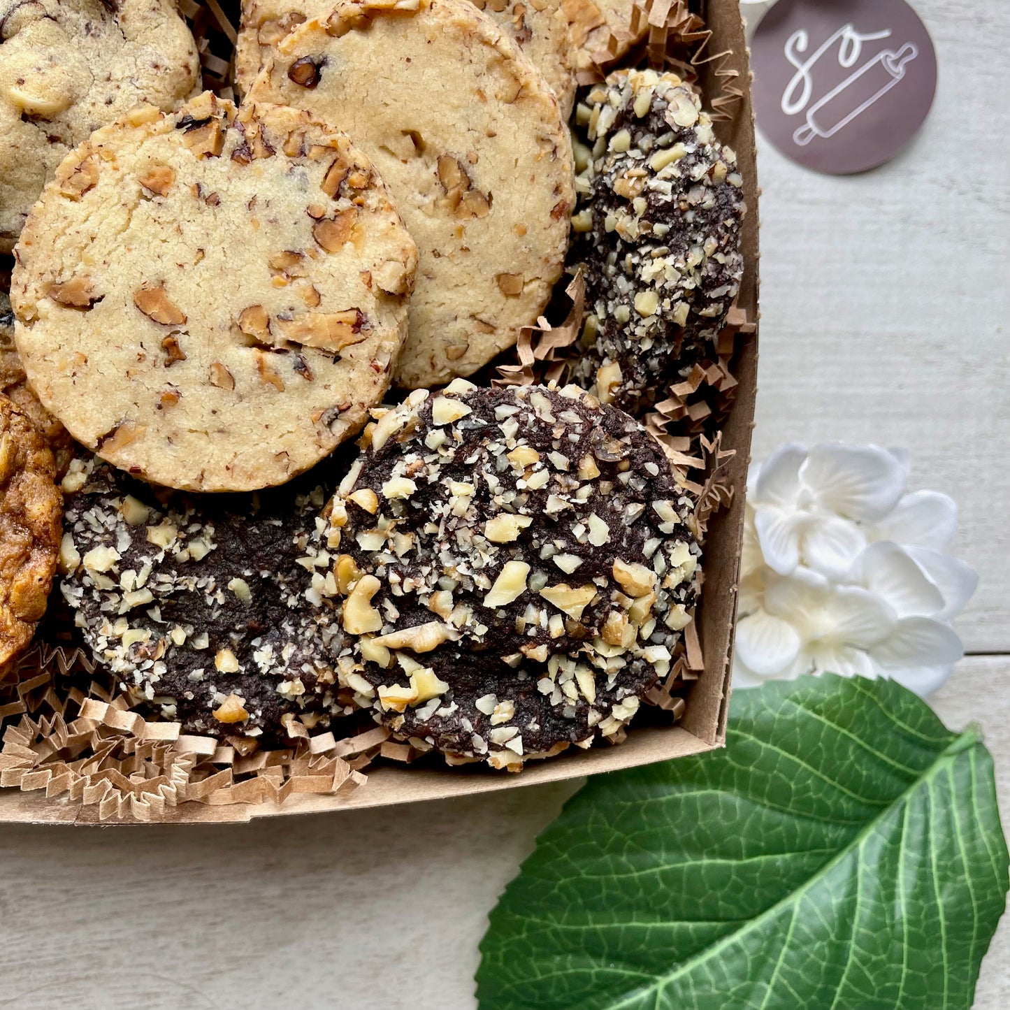 Assorted cookie gift box with maple pecan shortbread, double chocolate macadamia cookies, oatmeal raisin pecan cookies, and chocolate walnut cherry cookies.