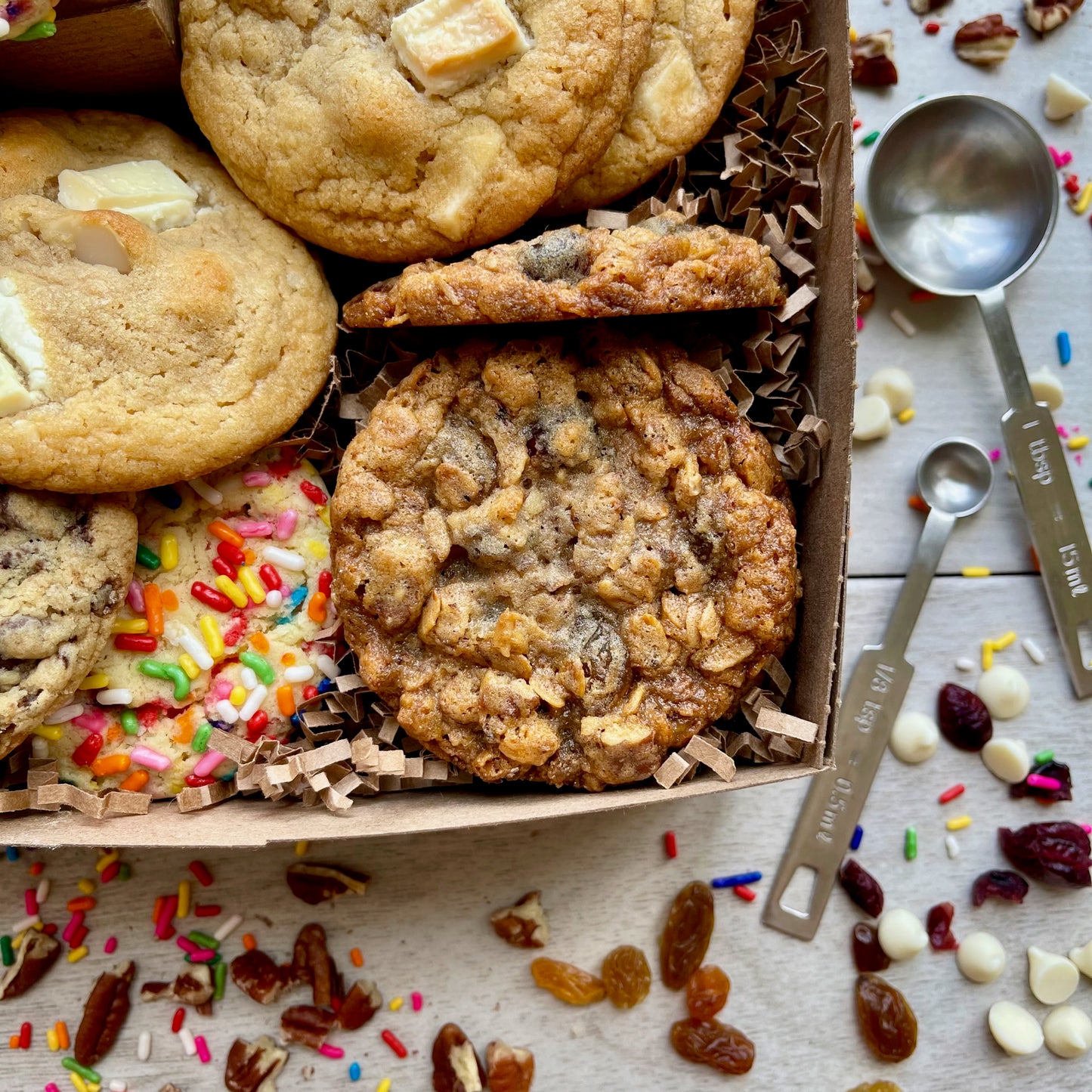 Assorted gift box with sprinkle cookies, chocolate chip cookies, white chocolate macadamia cookies, and oatmeal raisin cookies.